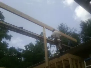 Carpenter setting a ridge beam over a new addition frame — Ice Dam Removal by Roofing Brothers in Mulliken