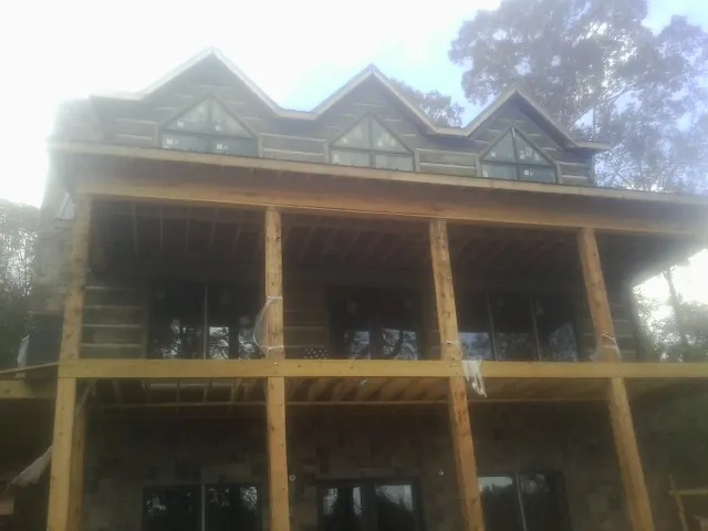 Dormers and porch framing on a large log home under construction — Roof Coating work by our crew in Mulliken