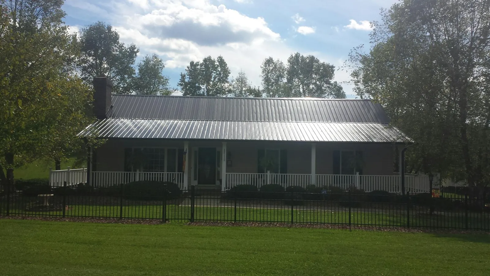 Gray metal roof on a brick ranch with a full width front porch — Gutter Guard Installation work by our crew in Mulliken