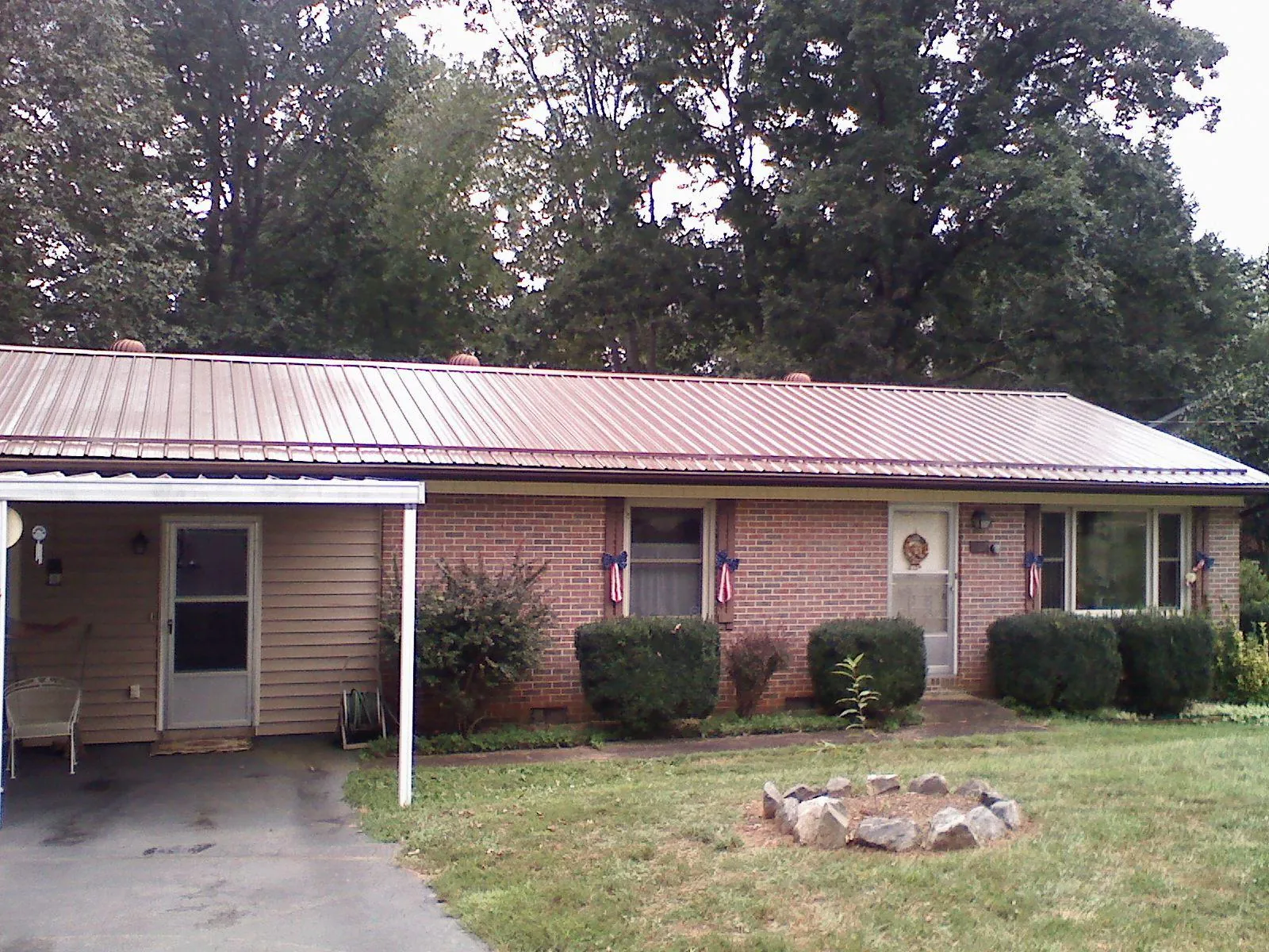 Bronze metal roof and carport on a brick ranch home — Roof Repair work by our crew in Mulliken