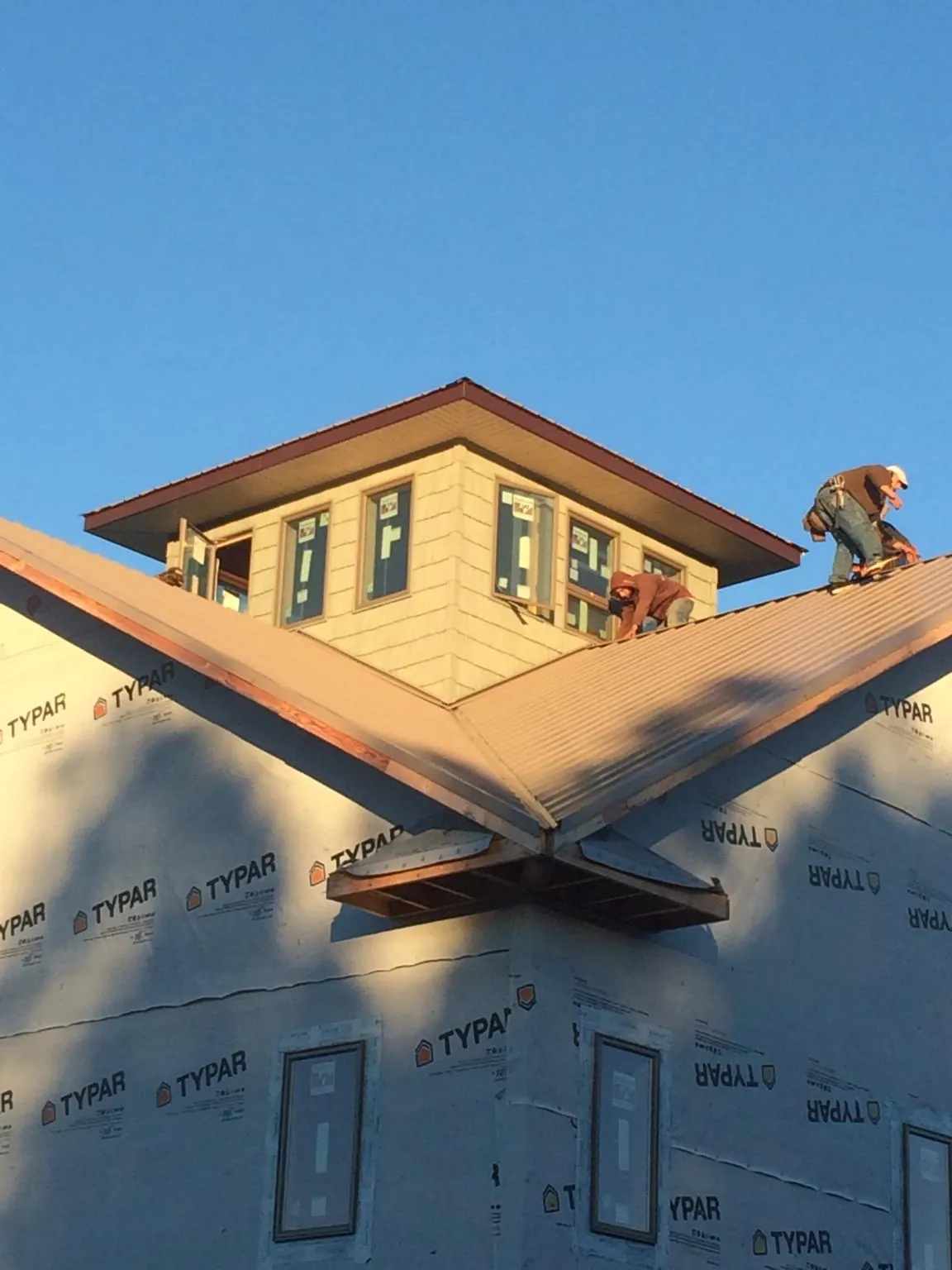 Roofers working around a rooftop cupola on a new metal roof at sunset — Roof Waterproofing in Mulliken by Roofing Brothers